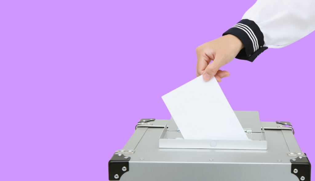 Hand wirft Zettel in Wahlurne