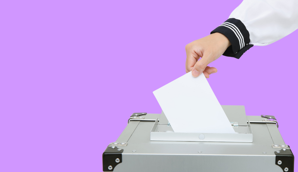 Hand wirft Zettel in Wahlurne