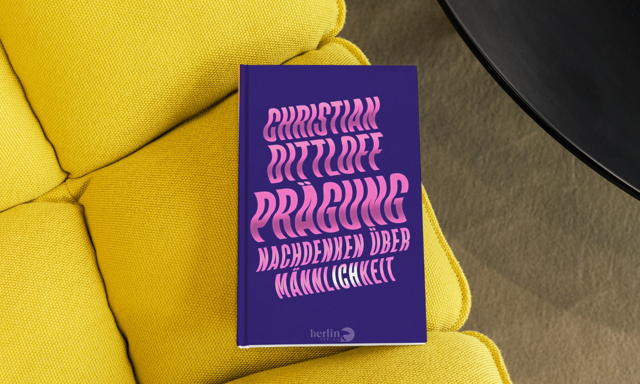Das Buch "Prägung: Nachdenken über Männlichkeit" liegt auf einem gelben Polster