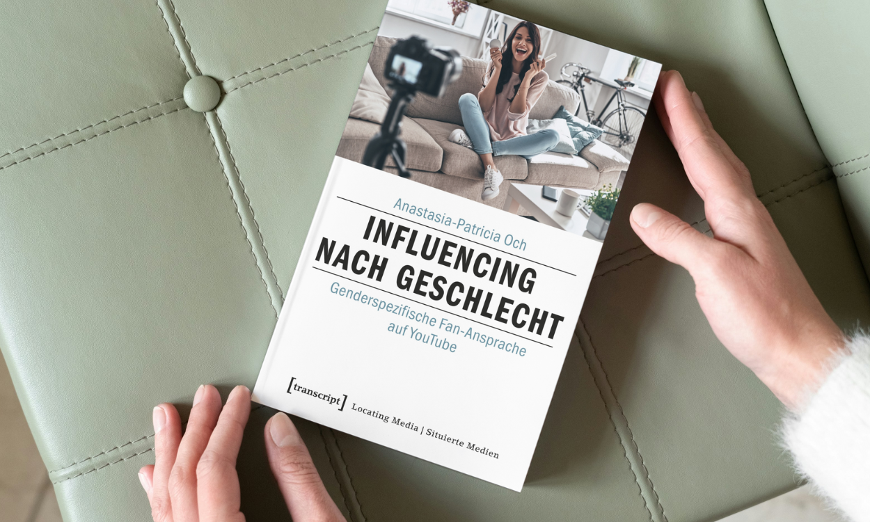Das Bild zeigt das Buchcover auf einer grünen Couch.